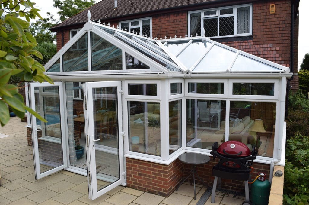 a victorian t-shaped conservatory with a barbeque outside