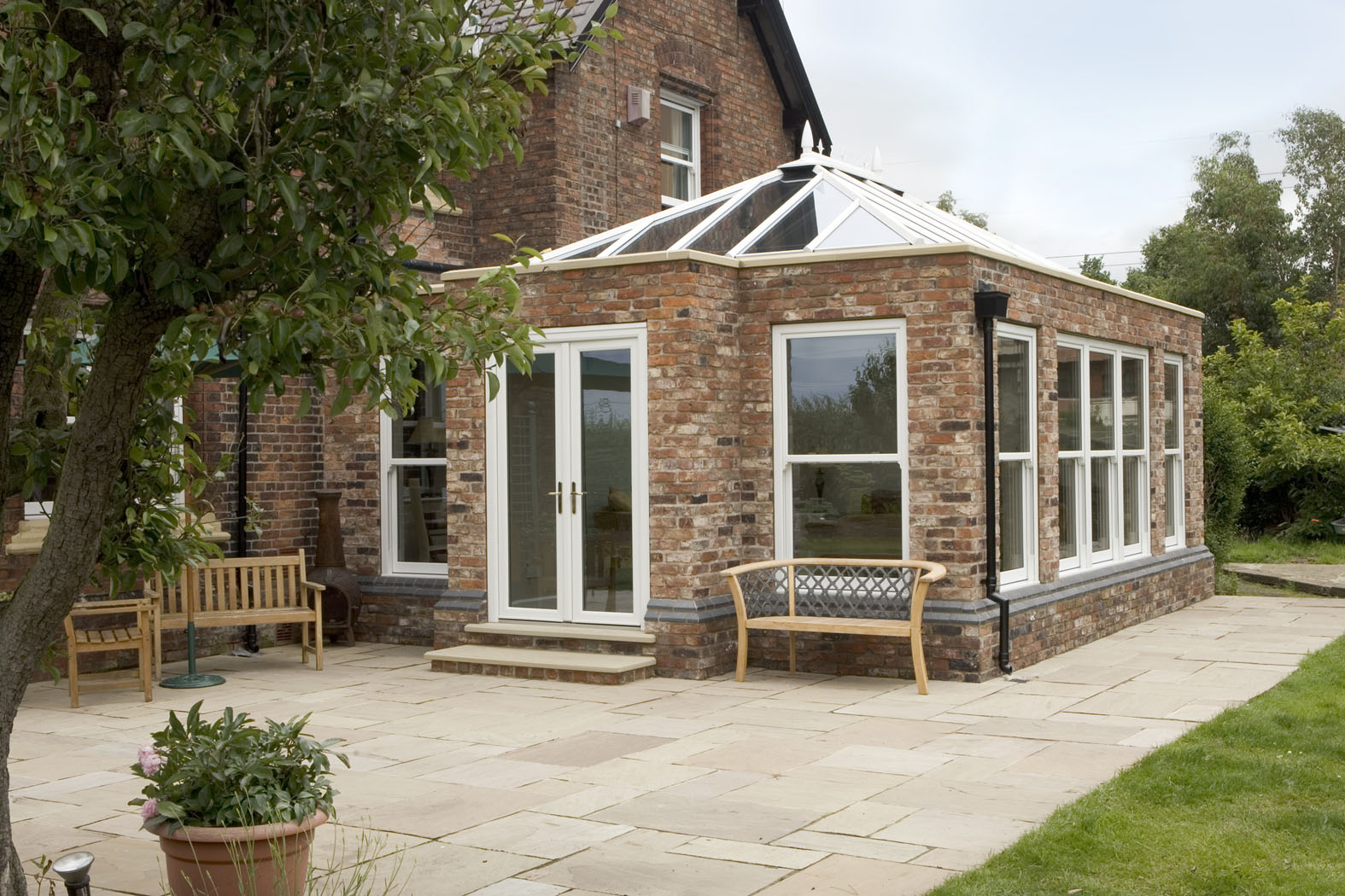 A brick patio displaying a large white circle, complementing the design of the adjacent orangery.