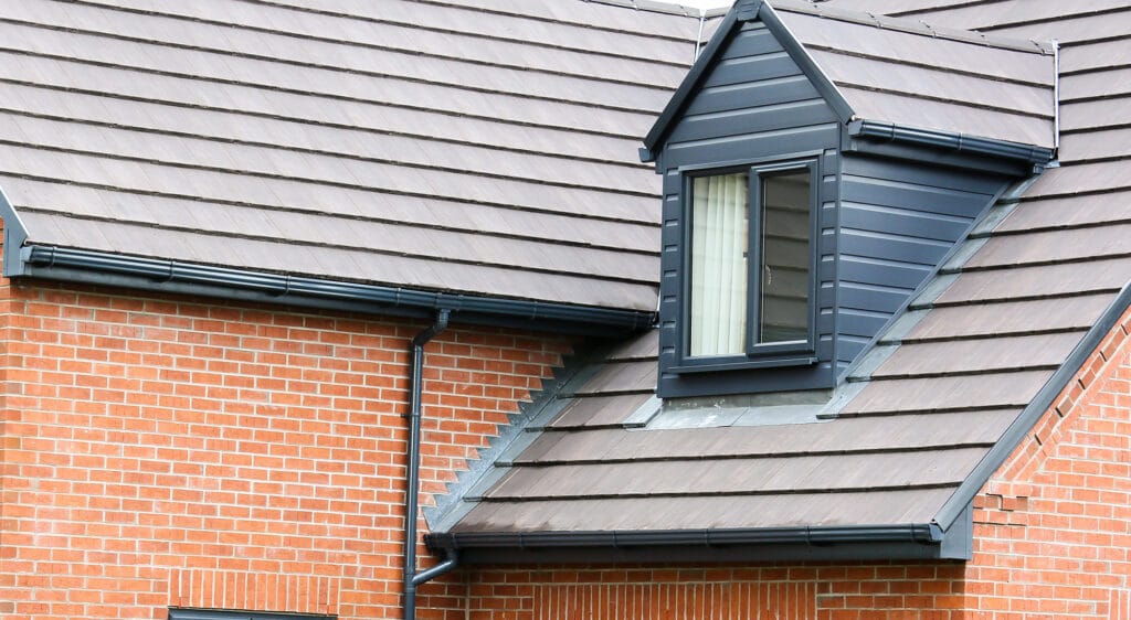 a roofline with black gutters and a upvc window