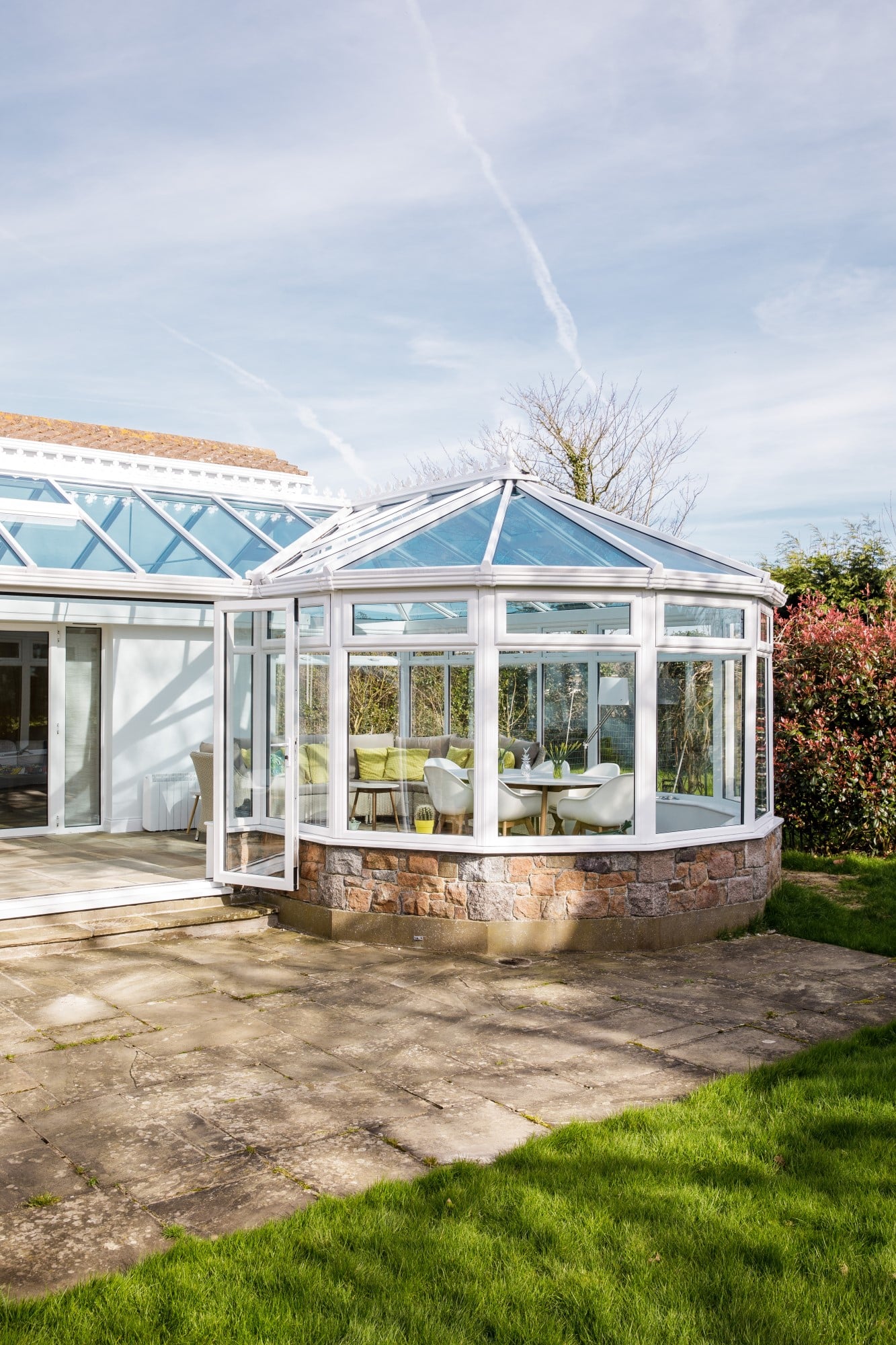 A large white house featuring a P-shaped conservatory with a striking glass roof.